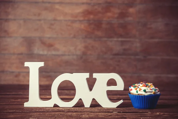 Cupcake and word Love on wooden table. — Stock Photo, Image