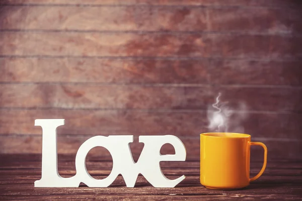 Té o taza de café con palabra Amor en la mesa de madera . — Foto de Stock