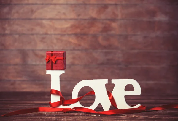 Pequeno presente e palavra Amor na mesa de madeira . — Fotografia de Stock
