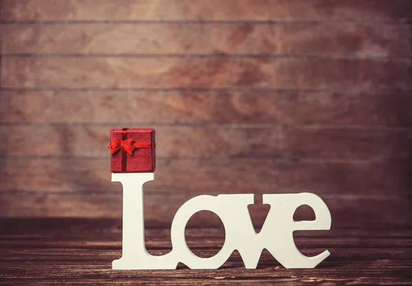 Pequeño regalo y palabra Amor en mesa de madera . —  Fotos de Stock