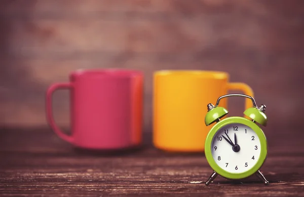 Two tea cup and alarm clock on wooden table. — Stock Photo, Image