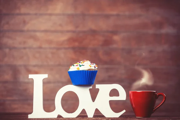 Cupcake, café e palavra Amor na mesa de madeira . — Fotografia de Stock