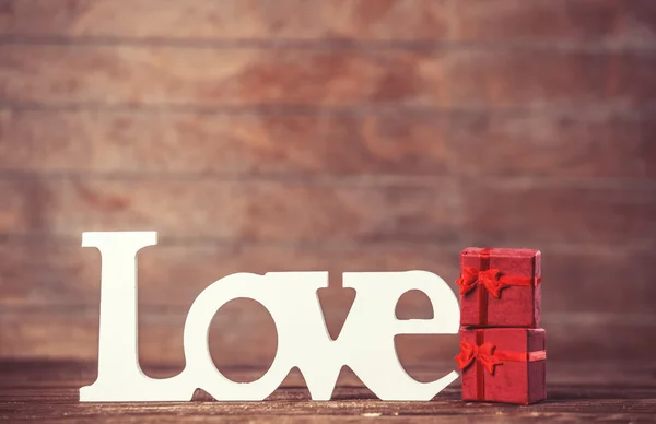 Pequeño regalo y palabra Amor en mesa de madera . —  Fotos de Stock