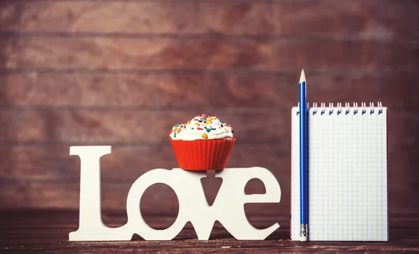 Cupcake, word Love and notebook with pencil — Stock Photo, Image