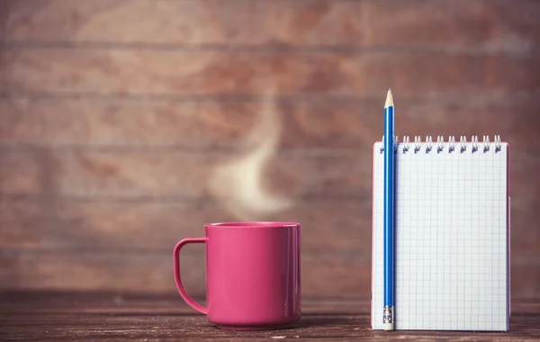 Taza de café y cuaderno sobre fondo de madera. — Foto de Stock