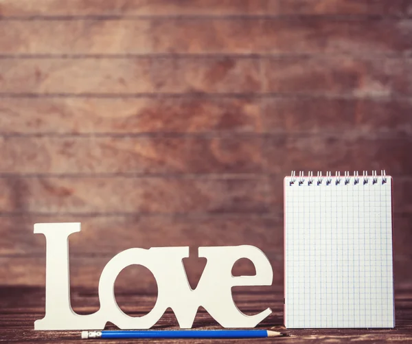 Ołówek i Notatnik rezygnować Wyraz miłości na tle drewniane. — Zdjęcie stockowe