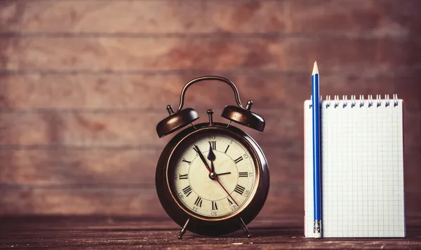 Reloj despertador y portátil sobre fondo de madera . —  Fotos de Stock