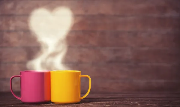 Two cups of coffee and heart shape on wooden background. — Stock Photo, Image