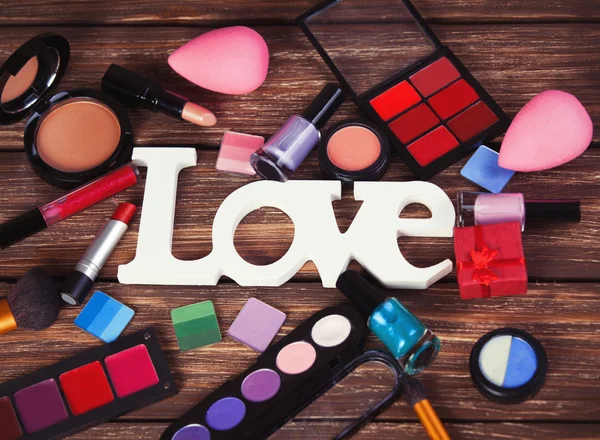 Cosmetics and word Love on wooden table — Stock Photo, Image