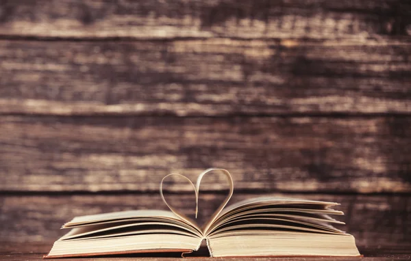 Vintage old books with heart shape on wooden table — Stock Photo, Image