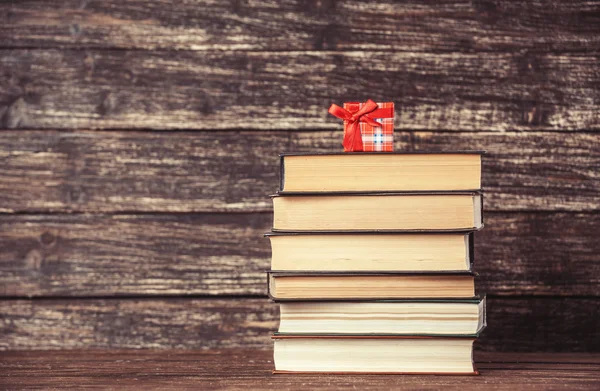 Regalo y libros sobre mesa de madera . — Foto de Stock