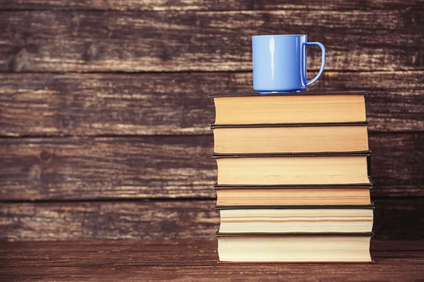 Boeken en kopje koffie op houten achtergrond. — Stockfoto