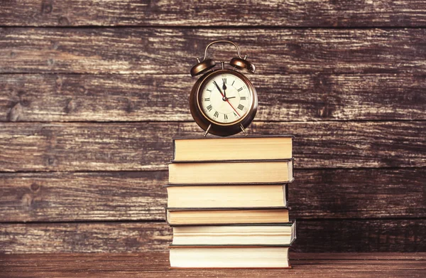 Reloj despertador y libros sobre mesa de madera . — Foto de Stock