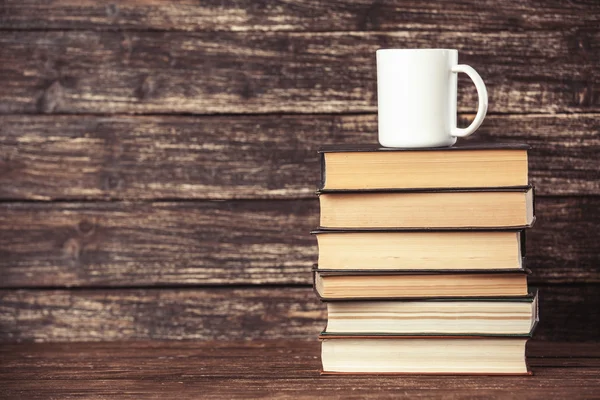 Boeken en kopje koffie op houten achtergrond. — Stockfoto