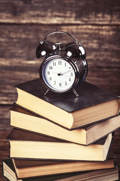 Relógio despertador e livros em mesa de madeira . — Fotografia de Stock