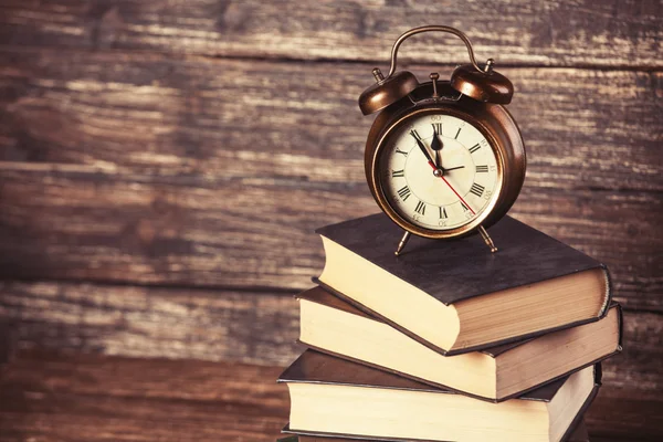 Relógio despertador e livros em mesa de madeira . — Fotografia de Stock