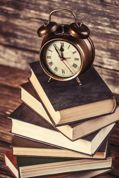 Wekker en boeken over houten tafel. — Stockfoto