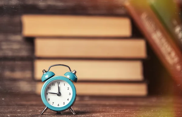 Wekker en boeken over houten tafel. — Stockfoto