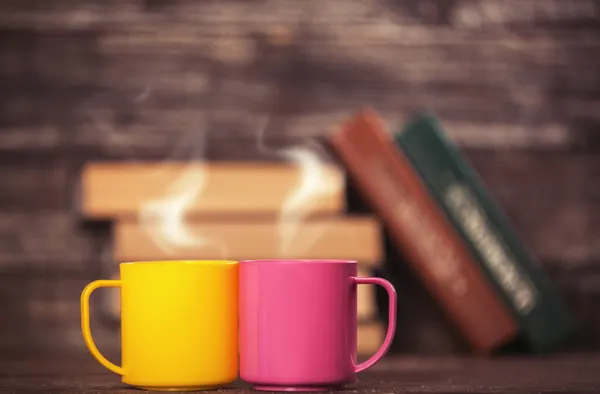 Two cups and books on background. — Stock Photo, Image