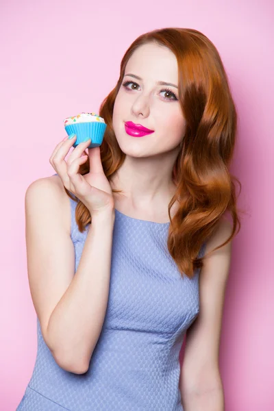 Menina ruiva com cupcake no fundo rosa . — Fotografia de Stock