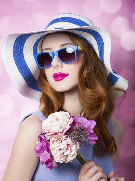 Ragazza rossa con fiori su sfondo rosa . — Foto Stock