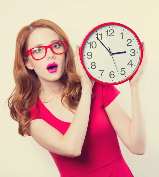 Surprised redhead girl with huge alarm clock on light background — Stock Photo, Image