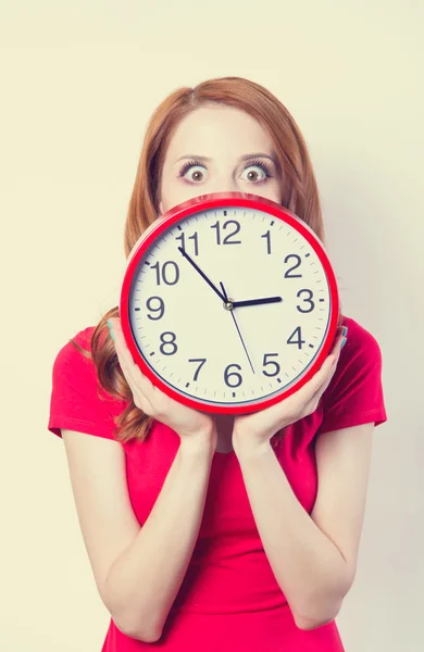 Surprised redhead girl with huge alarm clock on light background — Stock Photo, Image