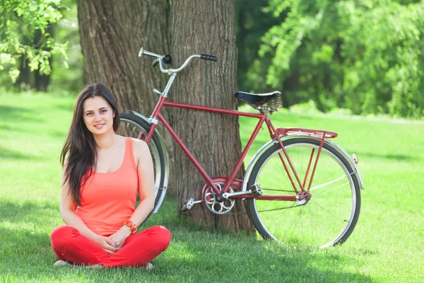 Menina feliz no parque com bicicleta no fundo . — Fotografia de Stock