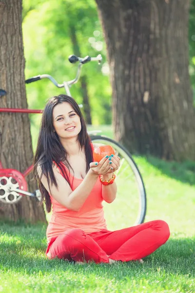 Menina morena com xícara de café no parque e com bicicleta em — Fotografia de Stock