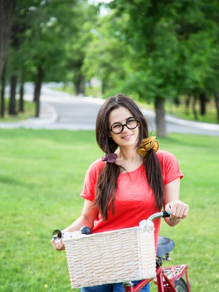Grappig meisje met fiets in het park. — Stockfoto