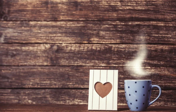 Telaio a forma di cuore e tazza di caffè su sfondo in legno . — Foto Stock