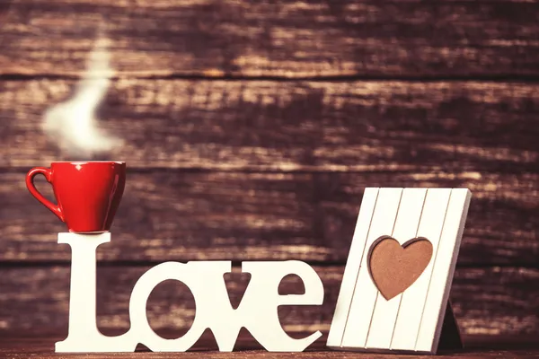 Coffee cup and Word Love with frame on wooden table. — Stock Photo, Image