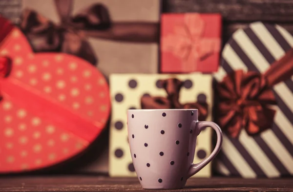 Cup of coffee and gifts on background. — Stock Photo, Image