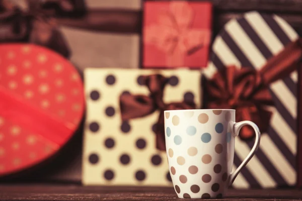 Cup of coffee and gifts on background. — Stock Photo, Image