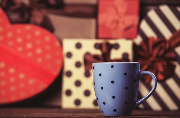 Tasse Kaffee und Geschenke im Hintergrund. — Stockfoto