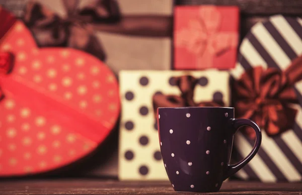 Taza de café y regalos en el fondo . —  Fotos de Stock