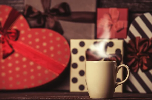Taza de café y regalos en el fondo . — Foto de Stock