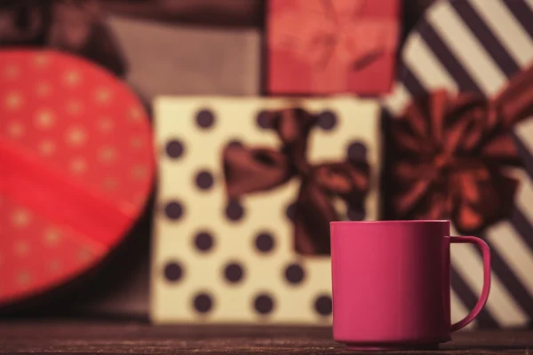Cup of coffee and gifts on background. — Stock Photo, Image