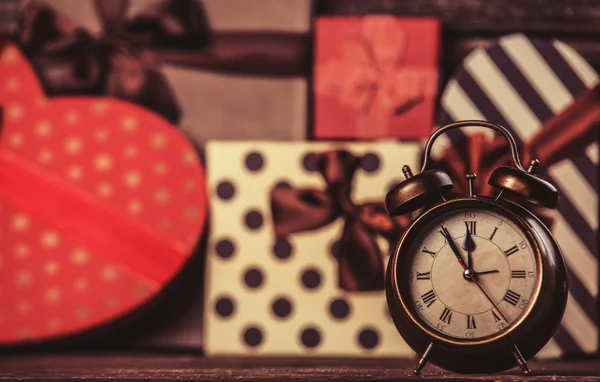 Alarm clock and gifts on background. — Stock Photo, Image