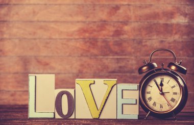 Çalar saat ve sözcük Aşk ahşap masada.
