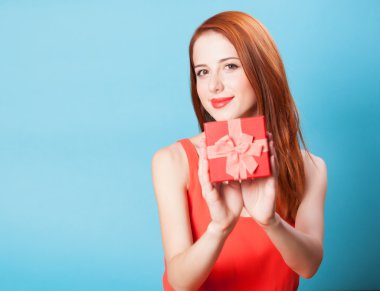 Kızıl saçlı kadınlara hediye üzerinde mavi arka plan ile gülümseyen.