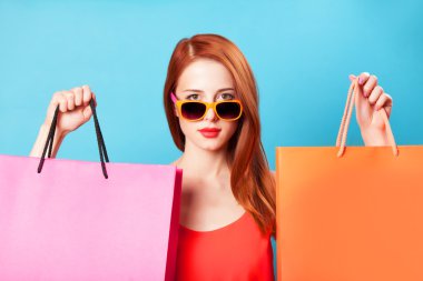 holding alışveriş torbaları üzerinde mavi arka plan stili Kızıl saçlı kadın.
