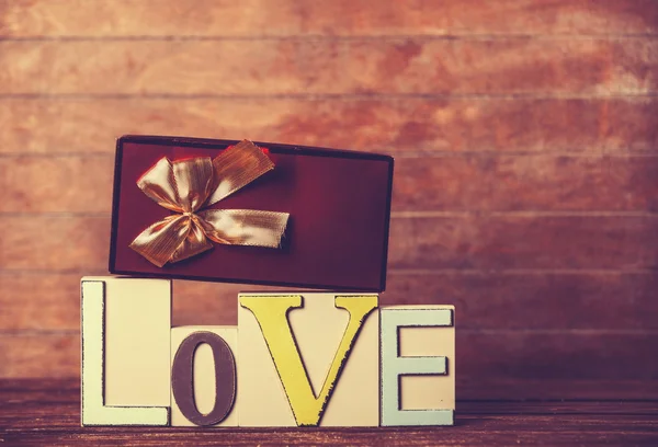 Pequeno presente e palavra Amor na mesa de madeira . — Fotografia de Stock