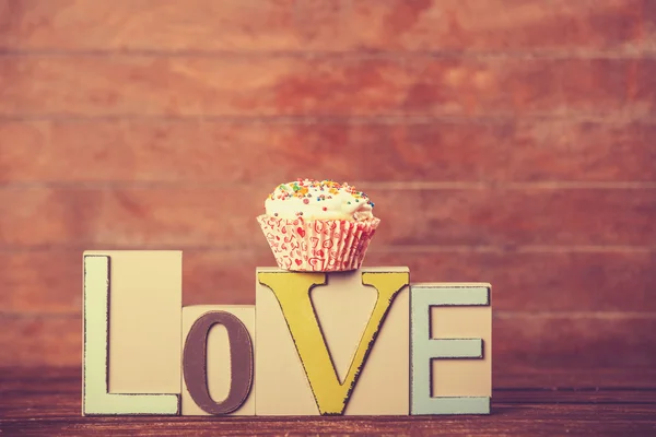 Cupcake and word Love on wooden table. — Stock Photo, Image