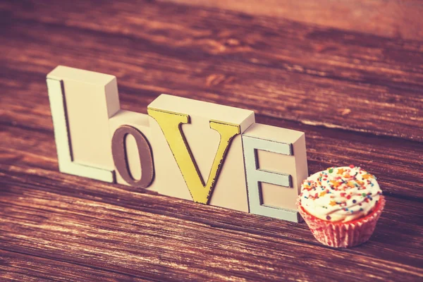 Cupcake and word Love on wooden table. — Stock Photo, Image