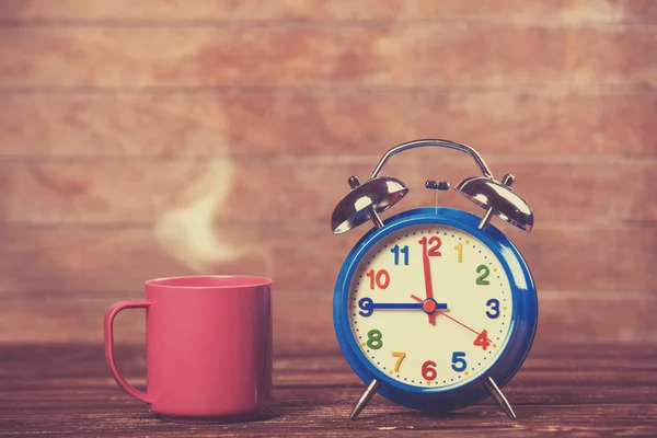 Cup of coffee and alarm clock on wooden table. — Stock Photo, Image