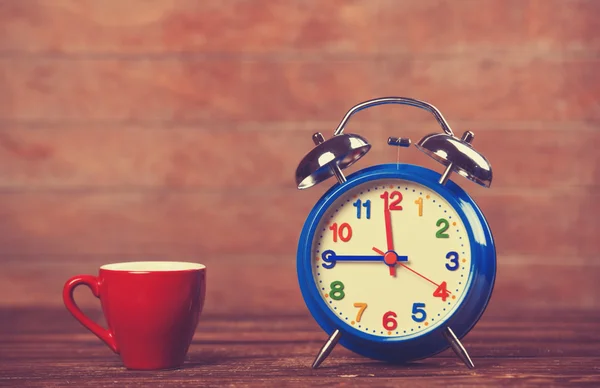 Kopje koffie en wekker op houten tafel. — Stockfoto