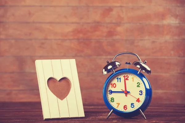 Reloj despertador retro y marco en una mesa . — Foto de Stock