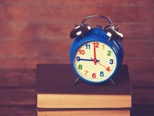 Reloj despertador y libros sobre mesa de madera . —  Fotos de Stock