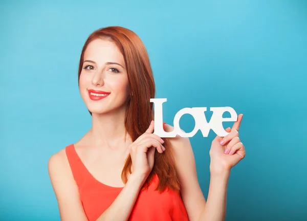 Feliz pelirroja de las mujeres con la palabra Amor sobre fondo azul . —  Fotos de Stock